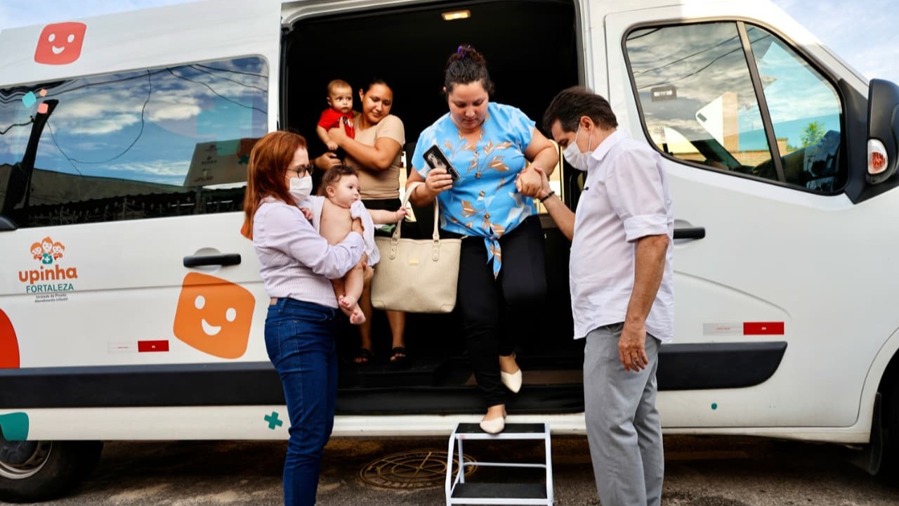 prefeito auxiliar uma mulher a descer de uma van enquanto dra. riane segura o filho da senhora no colo
